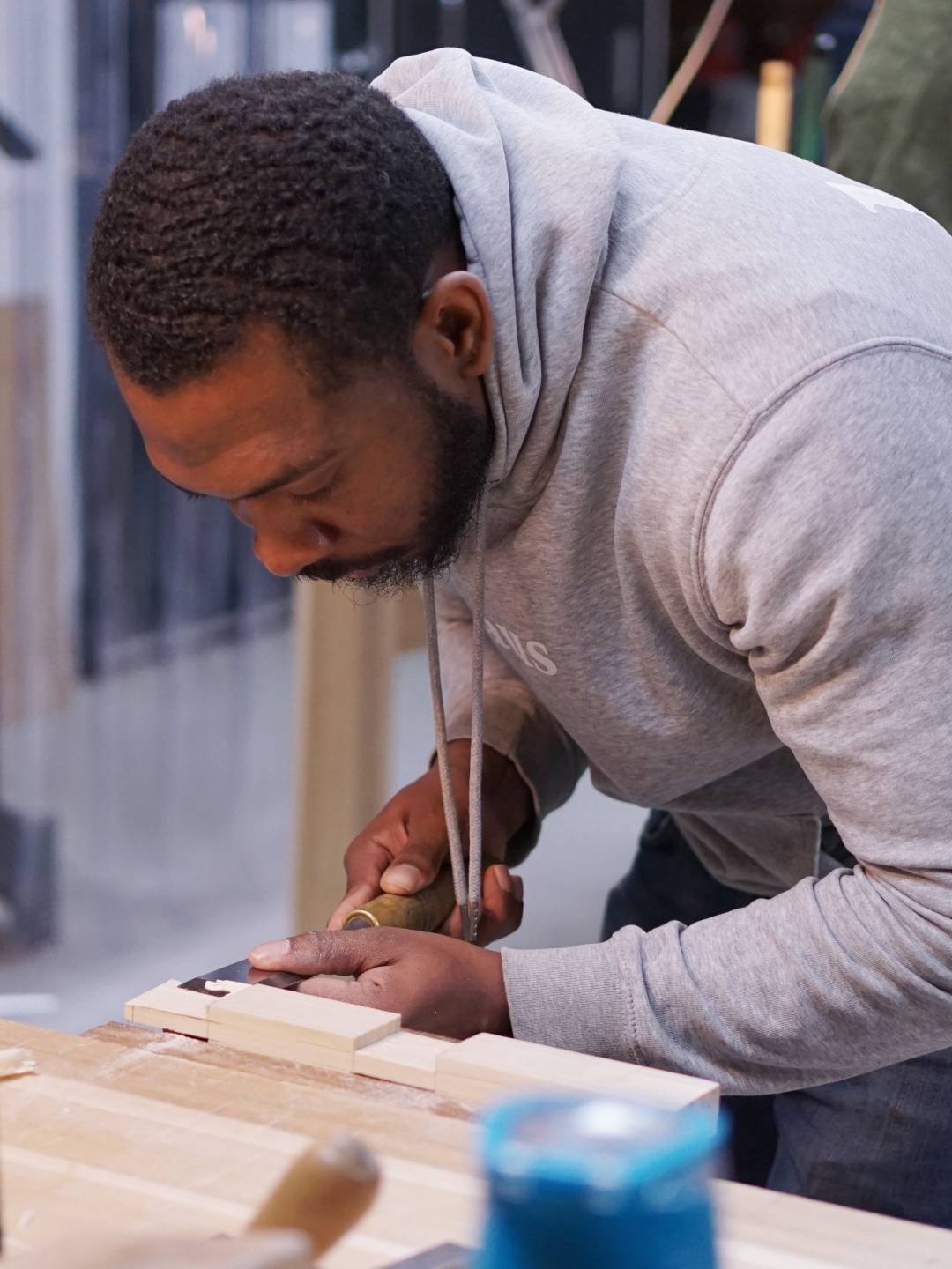 A man using a chisel to cut wood in a furniture making class