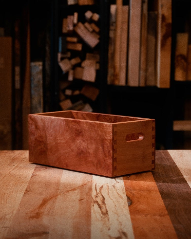 A pyx box made from London plane sitting on a striped wooden table